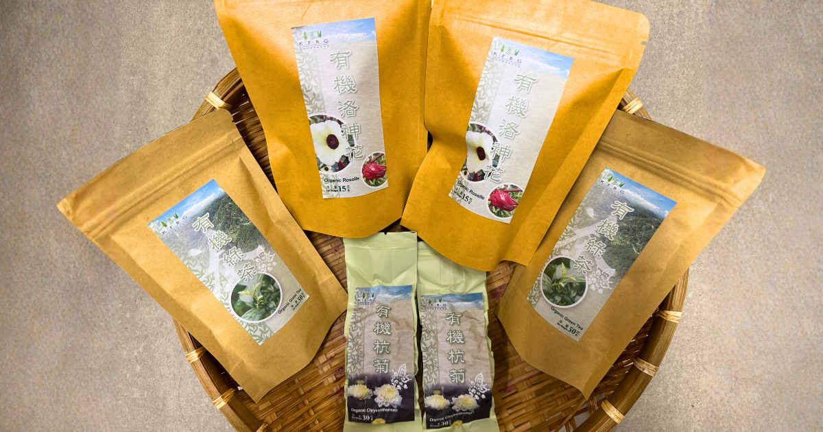 Packs of KFBG organic roselle, green tea and chrysanthemum arranged in a bamboo basket